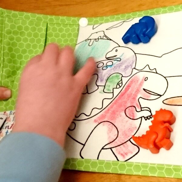 A child using a dinosaur-themed washable colouring mat